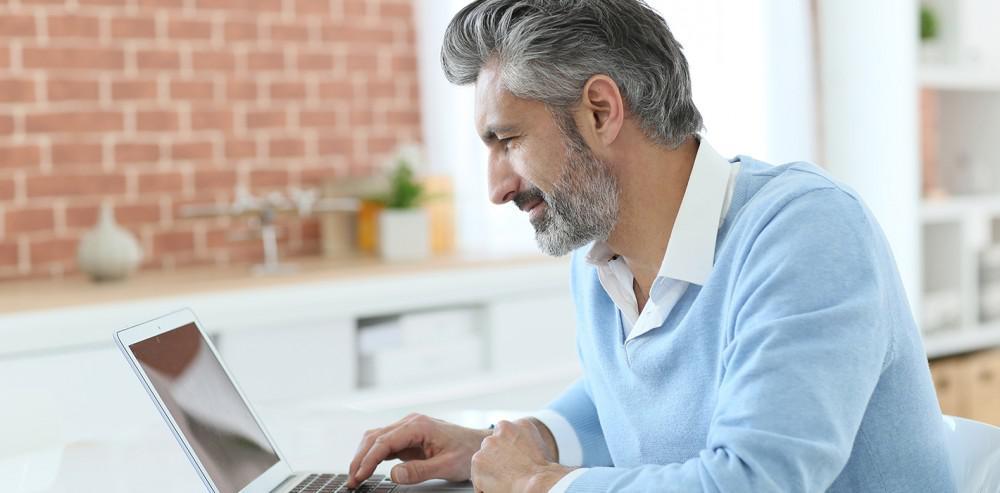 attractive silver haired bearded man on laptop